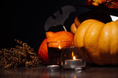 Cadılar Bayramı için bir ev dekorasyon için bir kompozisyon yalan sarı ve turuncu mumlar, bir mum yanıyor, büyük kara cadı şapkası