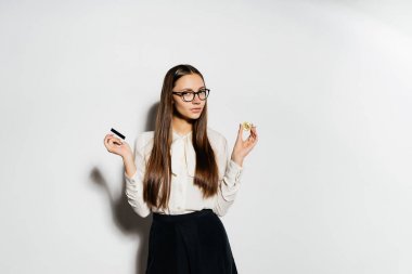 Gözlüklü genç modern bir başarılı kız bir banka kartı ve altın bitcoin tutuyor