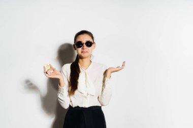 Gözlüklü genç modern bir başarılı kız bir banka kartı ve altın bitcoin tutuyor