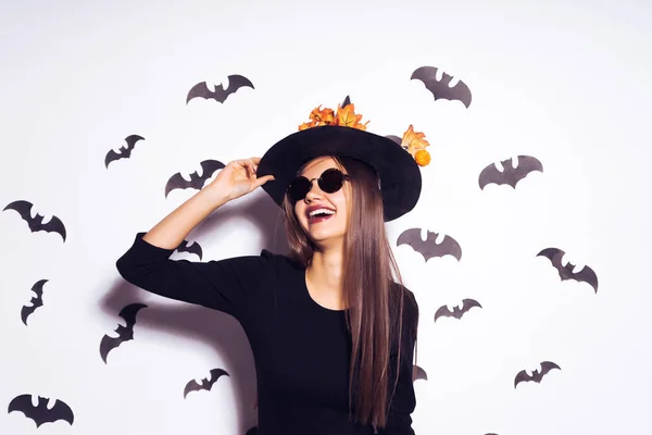 Mladá sexy gotická dívka oblečená v čarodějnice halloween, stál velký černý klobouk a sluneční brýle — Stock fotografie