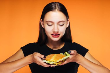 bir burger kız turuncu bir arka plan üzerinde tutar