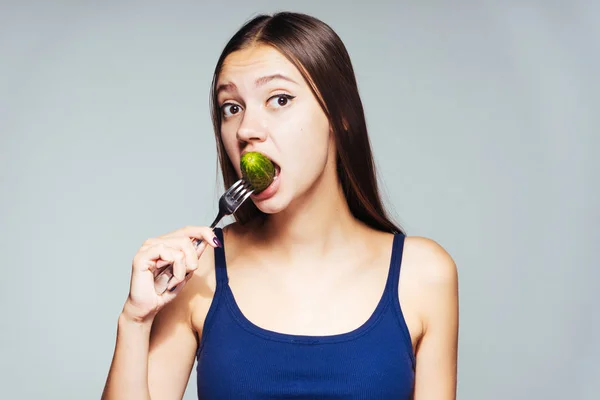 Une fille frustrée prend une bouchée d'un morceau de concombre — Photo