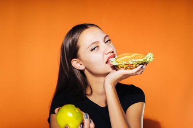 Kız diğer elinde bir elma yerine bir hamburger yiyor