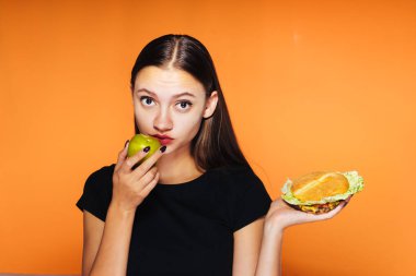 diğer elinde hamburger yerine bir elma yiyen kız