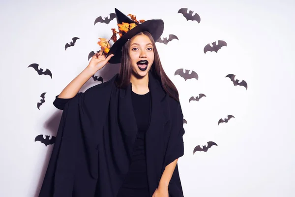 Een meisje in een heks kostuum is omgeven door vleermuizen — Stockfoto