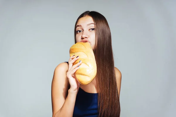 Lány egy fehér háttér, eszik egy vekni — Stock Fotó