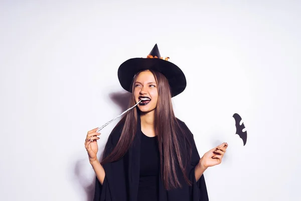 Uma menina em um terno de bruxa faz uma expressão astuta — Fotografia de Stock