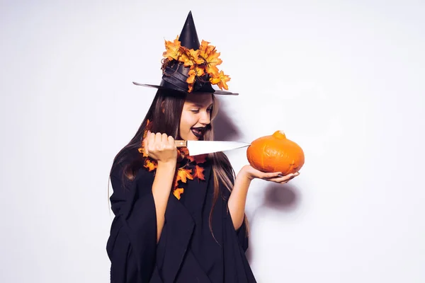 Una ragazza in costume di Halloween sta per tagliare una piccola zucca — Foto Stock