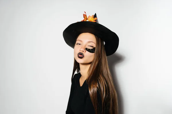 Girl in an unfinished witch suit sends an air kiss — Stock Photo, Image