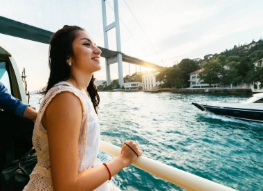 Genç özgürlük mutlu kız gün batımında tekne modern köprü altında seyahat