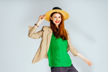 Kırmızı dudaklar ve parlak bir Yeşil bluz bir kız şapkasını el ve kahkaha ile tutar