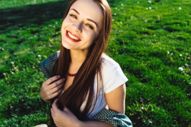 Sevimli gülümseyen çimenlerin üzerinde oturan kadın, kız kameraya bakıyor