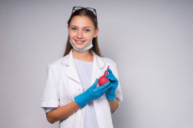 lovely and beautiful girl in a white lab coat and medical gloves holds a medical pear smiles and looks at the camera, isolated clipart
