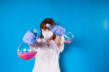 bir kadın beyaz bir elbise ve bir maske takarak yalıtım şişeye reaktifleri balonun üzerinden dökülür