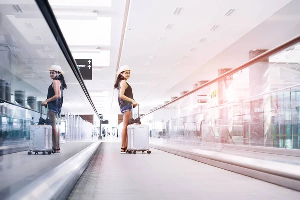 Young teen woman with hand luggage,suitcase carrying on escalator in international airport terminal. Traveler on vacations — Stock Photo, Image