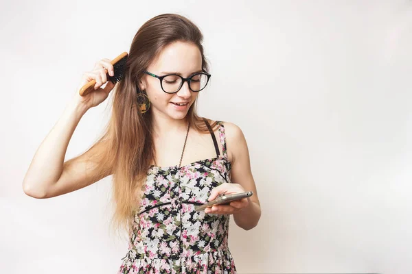 Vrouw met haar kam het texting, glimlachen, mooie langharige meisje — Stockfoto