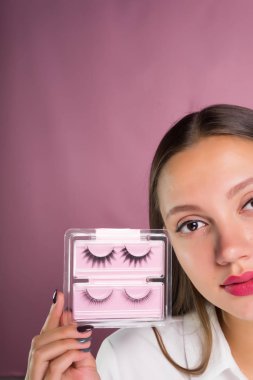 bir paket siyah sahte kirpik tutan genç güzel kız