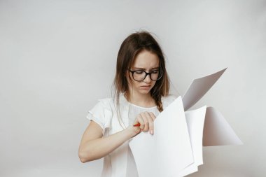 Bir genç güzel kız gözlük ve beyaz bir T-shirt kağıtları, üzgün görünüyor bir çok tutar