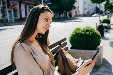 genç güzel kız ahşap bir bankta oturan selfie yapıyor