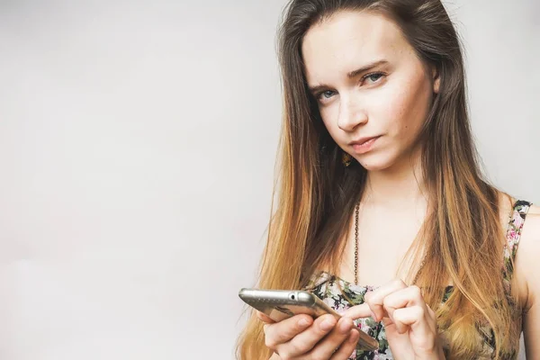 Mulher jovem cético olhando no smartphone, escreve em seu smartphone — Fotografia de Stock