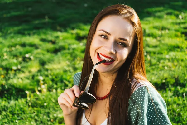 Femme souriante tient des lunettes de soleil, copyspace.With lunettes, autour de l'herbe verte — Photo