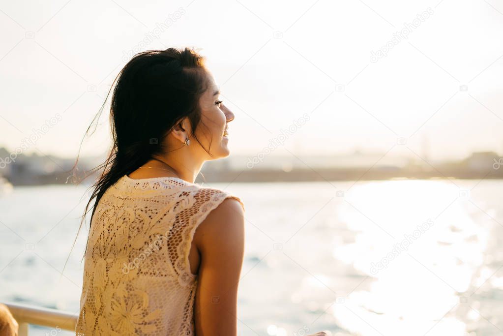 A girl enjoying the sunset during a boat trip. Back view