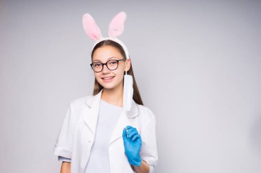 gülümseyerek, mavi medikal eldiven giymiş bir genç kız tavşan kulakları ve gözlük, şeklinde bir RIM ile