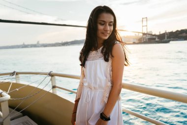 Genç kız gezgin bir yatta seyir ederken gün batımı, modern ünlü köprü arka plan üzerinde seyir rahatlatır