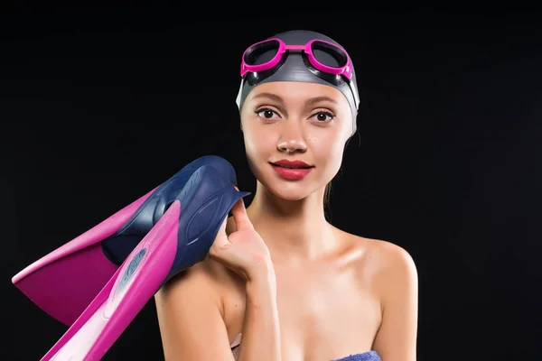 Jovem sorrindo menina bonita em um boné de natação e óculos segurando nadadeiras nas mãos — Fotografia de Stock