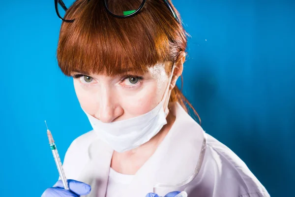 Maturo medico donna dai capelli rossi in maschera medica protettiva tiene siringa in mano — Foto Stock