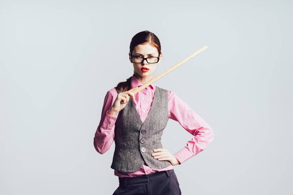 a young modern successful girl in a gray office vest and glasses is holding a teacher's pointer