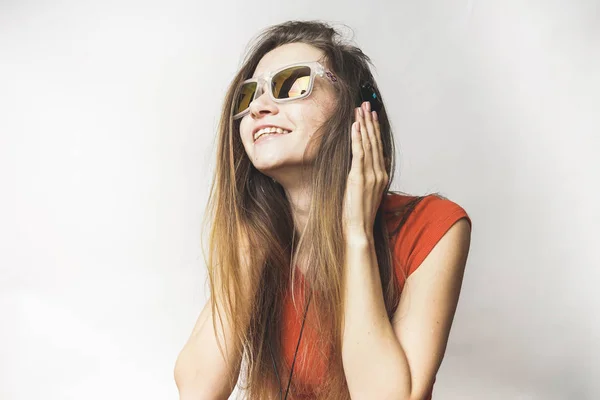 Joven chica sonriente en gafas de sol escuchando música en auriculares grandes — Foto de Stock