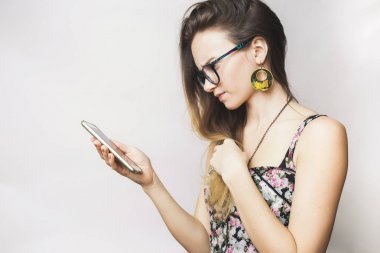 gözlük ve büyük küpeler ile genç üzgün kız onun smartphone görünüyor