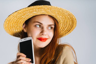 genç güzel kız bir hasır şapka ve kırmızı ruj ile bir akıllı telefon elinde tutan ve gizemli bir şekilde kenara bak