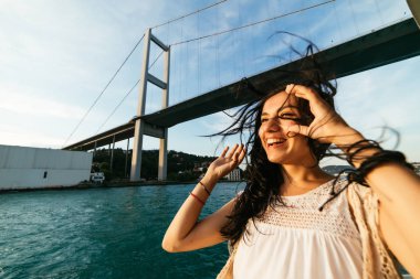 Genç özgürlük mutlu kız tekne ile seyahat etmek su ünlü modern Köprüsü yakınlarında görünümü
