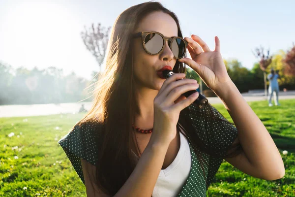 Felice moda sorridente Donna in occhiali da sole fumo vaporizzatore sulla strada, fumo — Foto Stock