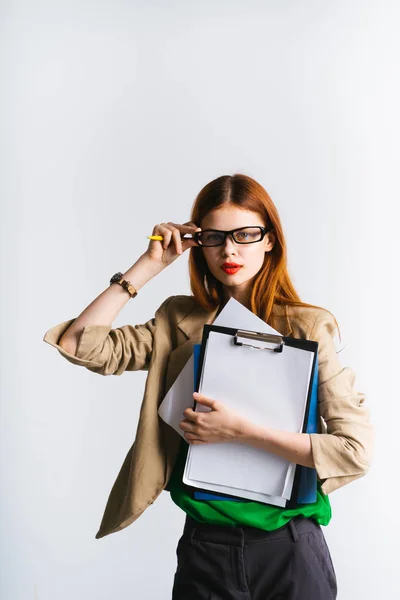 Ein modernes selbstbewusstes junges Mädchen mit Brille hält einen Ordner mit wichtigen Dokumenten in der Hand und justiert ihre Brille — Stockfoto