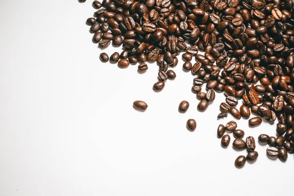 На білій поверхні красиво лежать запашні кавові зерна — стокове фото