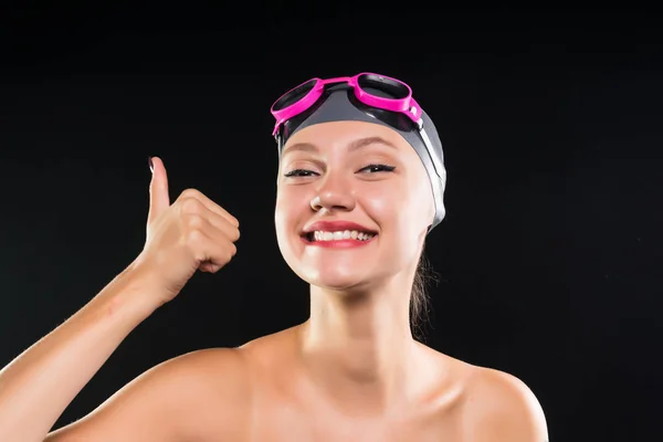 Jovem menina sorridente feliz em um boné de natação e óculos mostra um polegar para cima — Fotografia de Stock