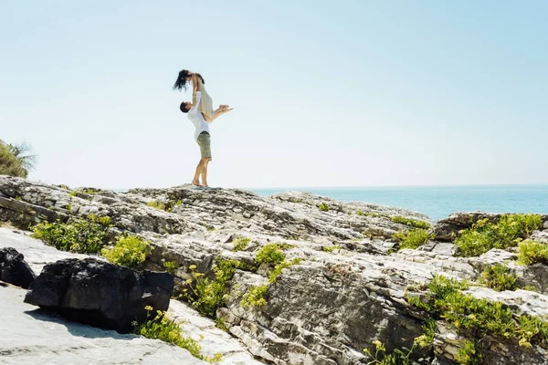 Un uomo tiene una ragazza tra le braccia in lontananza sullo sfondo dell'oceano — Foto Stock