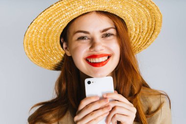 Hasır Şapkalı genç mutlu Kızıl saçlı kız bir telefon el ve gülümsüyor tutar