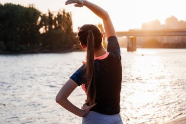 Güneşin nehir kıyısında uzanan genç spor kız