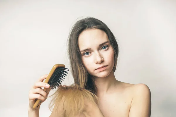 Bella ragazza pettinando i capelli lunghi con un pettine di legno — Foto Stock