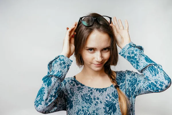 Young beautiful pretty girl smiles and puts on glasses — Stock Photo, Image