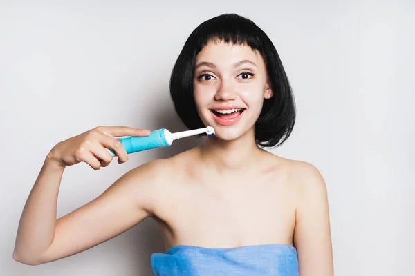 Jovem menina bonita com cabelo preto curto, sorrindo, segurando uma escova de dentes nas mãos — Fotografia de Stock