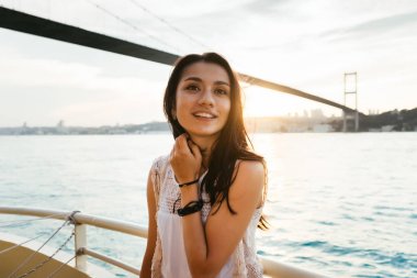 Günbatımı ve gülüyor modern bir köprünün altında bir güzel Latin kız bir yatta yelken