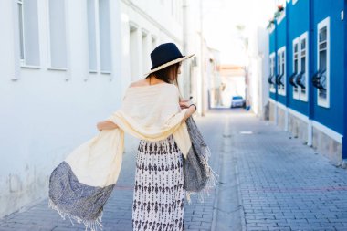 Şapkalı bir genç kız eski şehir Arnavut kaldırımlı bir cadde boyunca yürüyor