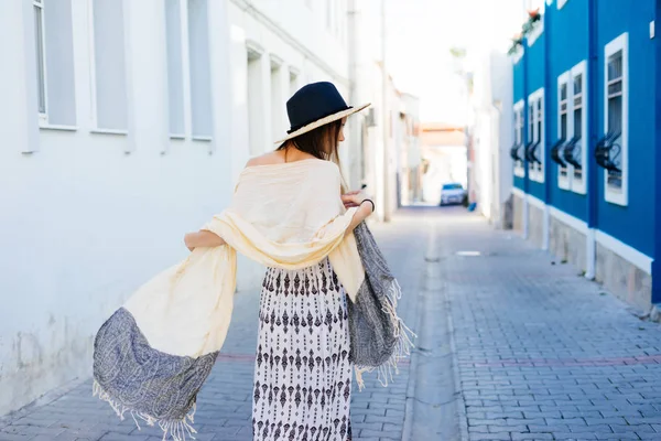 Şapkalı bir genç kız eski şehir Arnavut kaldırımlı bir cadde boyunca yürüyor