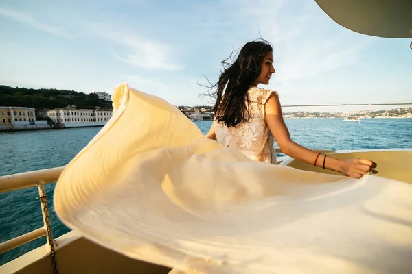 Una ragazza felice si erge su una barca al tramonto, una romantica vista sul Bosforo e sul ponte — Foto Stock