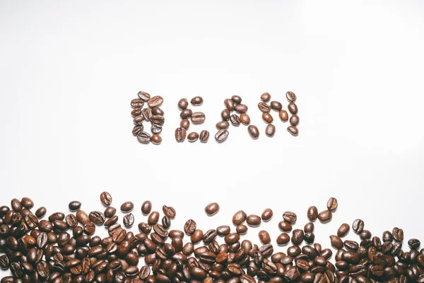 Beyaz yüzeyde güzel kokulu kahve, kelime fasulye atılır tahıl taneleri yalan